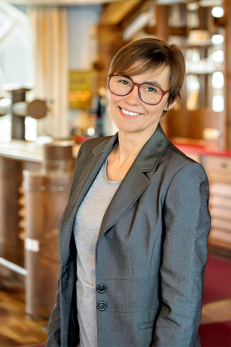 Auf dem Bild ist Magdalena Mazelle vom Mazelle Photography Fotostudio® zu sehen, gekleidet in einem eleganten grauen Damenanzug im amerikanischen Schnitt. Die Aufnahme entstand kurz vor einer Hochzeit im Trauraum der Seebrücke Sellin auf Rügen. Die Szene zeigt ihre ruhige, konzentrierte Präsenz unmittelbar vor Beginn der fotografischen Begleitung – ein Moment zwischen professioneller Vorbereitung, klarer Haltung und der charakteristischen ästhetischen Linie des Mazelle‑Studios.